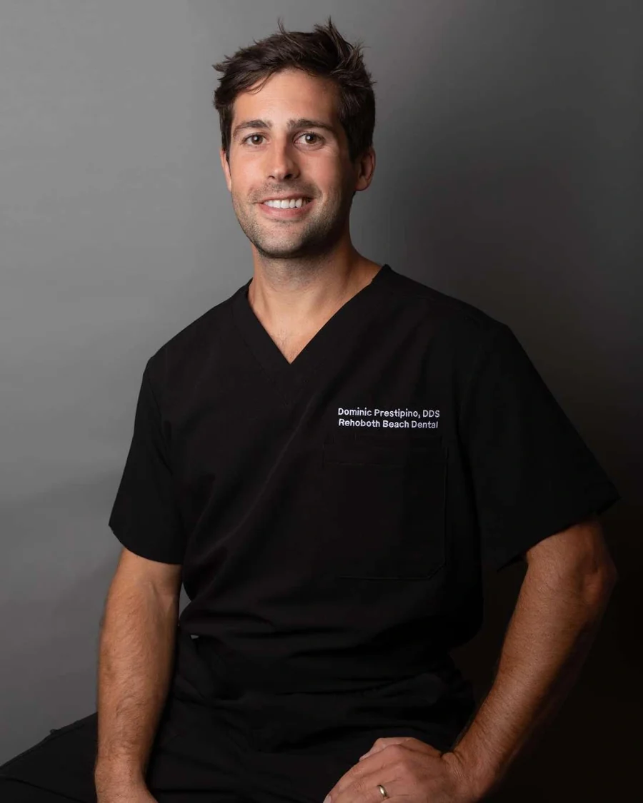Dr. Dominic Prestipino, DDS, owner of Rehoboth Beach Dental, in black scrubs.